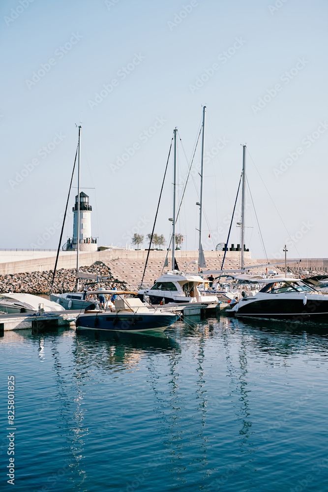 Row of motor boats moored at a breakwater with a lighthouse