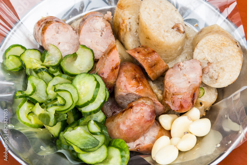 Close-up of Taiwanese sausage and sticky rice (glutinous rice) sausage on a plate, with some garlic and cucumber. This is one of the street snacks popular among tourists in Taiwan.