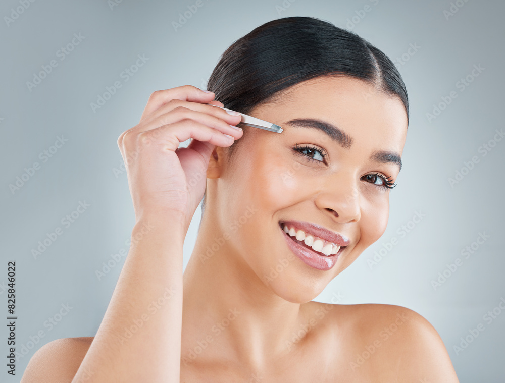 Portrait, woman and tweezers for eyebrow in studio for grooming, self care or hair removal routine. Smile, cosmetic and female person with epilation tool for plucking face isolated by gray background