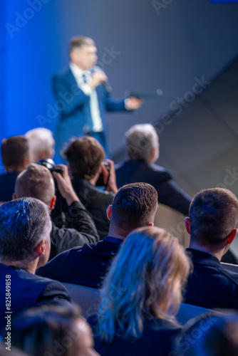 Wallpaper Mural Speaker is addressing an audience at a business conference. People in the audience are paying attention and some are taking photos. Torontodigital.ca