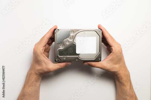 Man's hands showing a hard drive from a desktop computer close-up on a white background photo