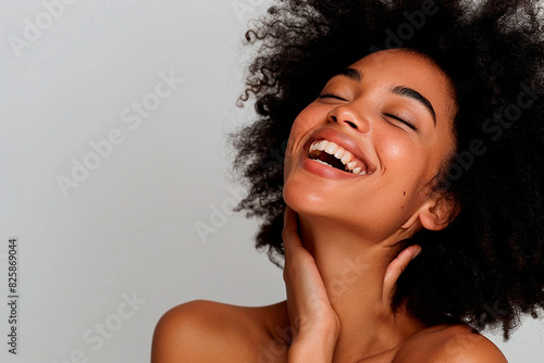 A woman with curly hair is smiling and her teeth are showing