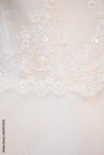 A closeup view of a delicate white lace fabric featuring intricate floral embroidery and shimmering sequins