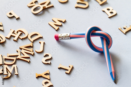 Pencil with knot and scattered letters, dyslexia concept