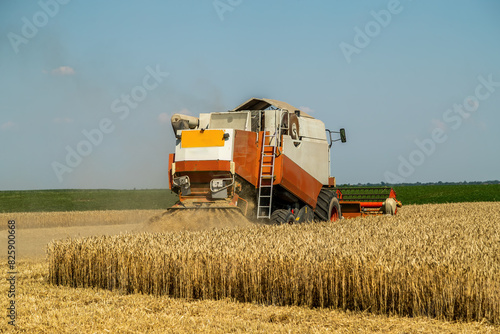 Combine harvester at work on a wheat field under a clear blue sky