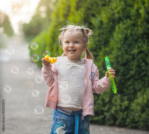 three years old caucasian child girl blowing soap bubbles in the park. happy carefree childhood