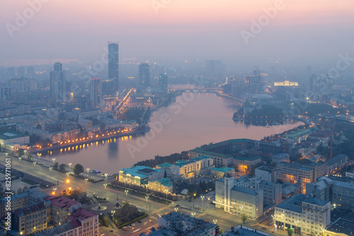 Top view of the city of Yekaterinburg, Sverdlovsk region, Russia. Beautiful cityscape. Aerial view of the City Pond, streets, buildings and skyscrapers. Evening twilight and haze.