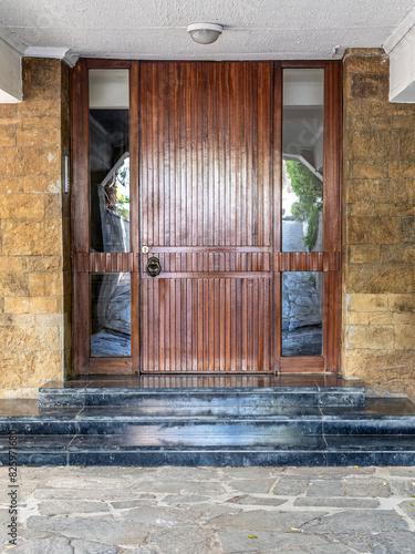 A classic design house entrance with a wooden door between glass openings. Travel to Athens, Greece.