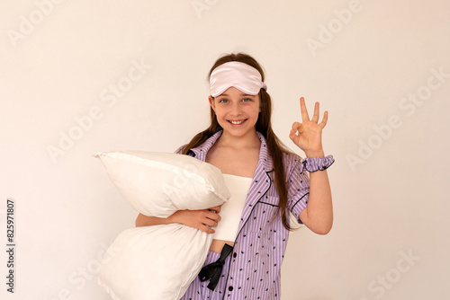 Girl making peace sign while holding pillow, playful pose. (ID: 825971807)