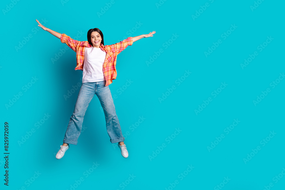 Full size photo of nice young girl jump empty space wear plaid shirt isolated on teal color background Full size photo of nice young girl jump empty space wear plaid shirt isolated on teal color background