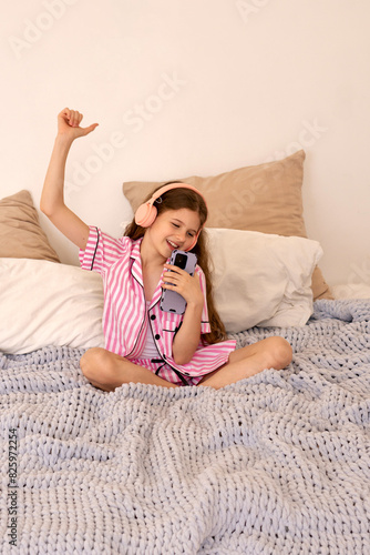 Young girl singing into smartphone, wearing headphones (ID: 825972254)