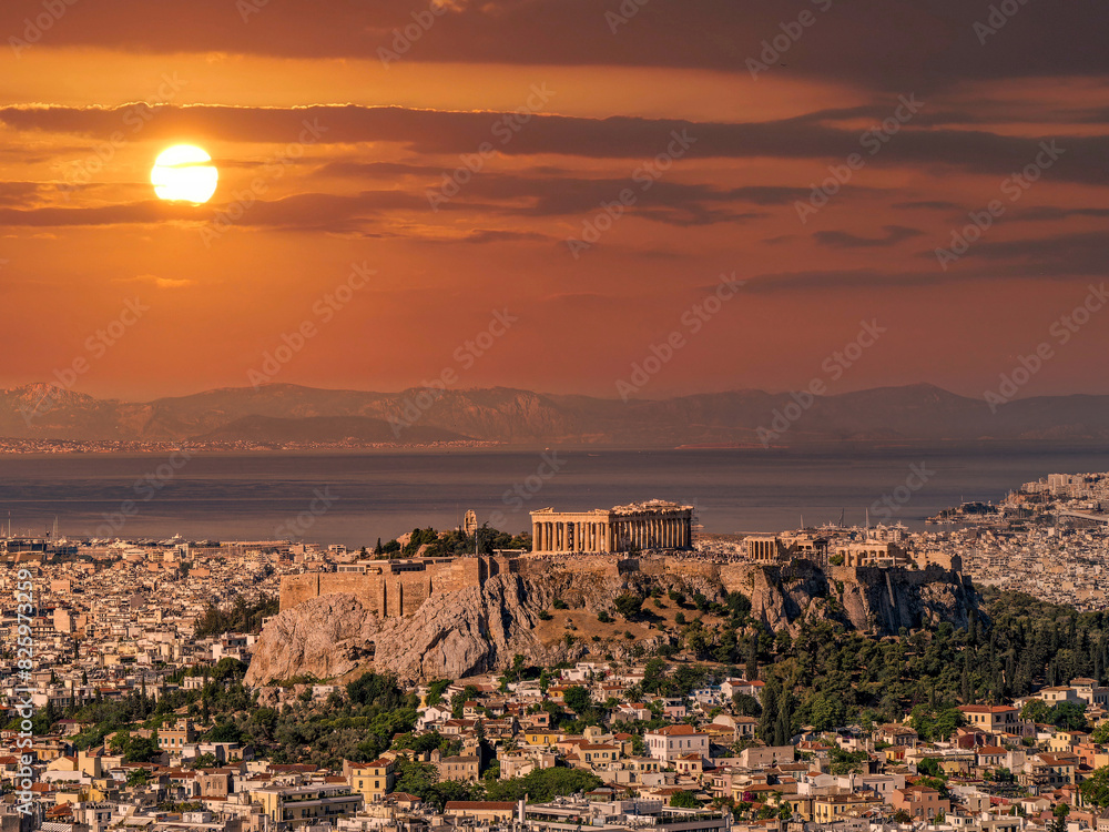 Obraz premium Panoramic view of Athens with Parthenon on the Acropolis and the Saronic sea in the background under a fiery sky. Travel to Greece.
