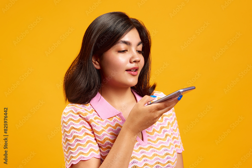 Portrait of you Indian girl talking on smartphone against vibrant yellow studio background. Customer. Ordering. Concept of human emotions, fashion and style, beauty, social media and internet. Portrait of you Indian girl talking on smartphone against vibrant yellow studio background. Customer. Ordering. Concept of human emotions, fashion and style, beauty, social media and internet.