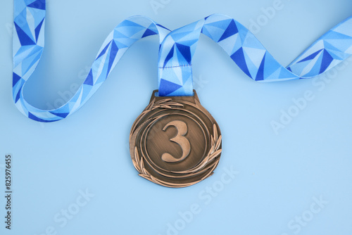 Bronze medal with blue ribbon on blue background.