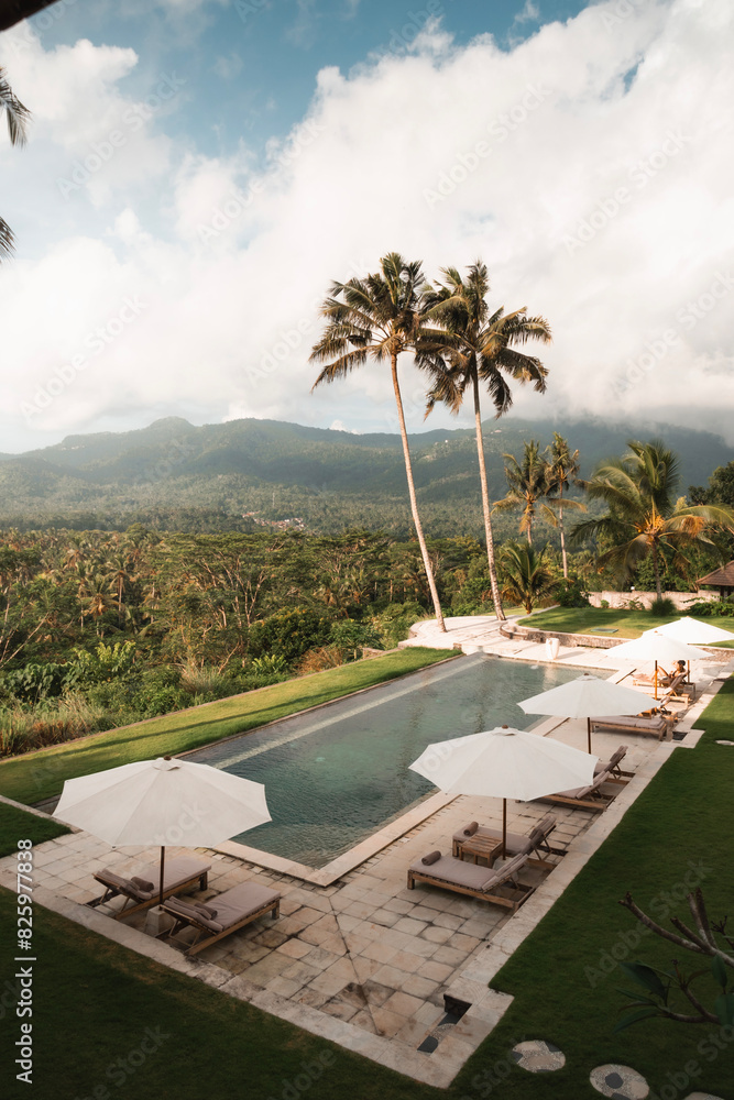 Fototapeta premium Paradise hotel with pool surrounded by palm trees on the tropical island of Bali
