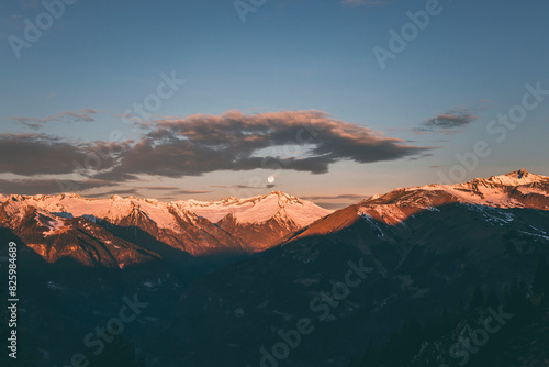 sunrise over the mountains with clouds and full moon