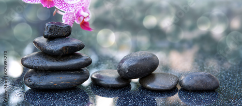 Black spa stone and pink orchid flowers on the gray table background.