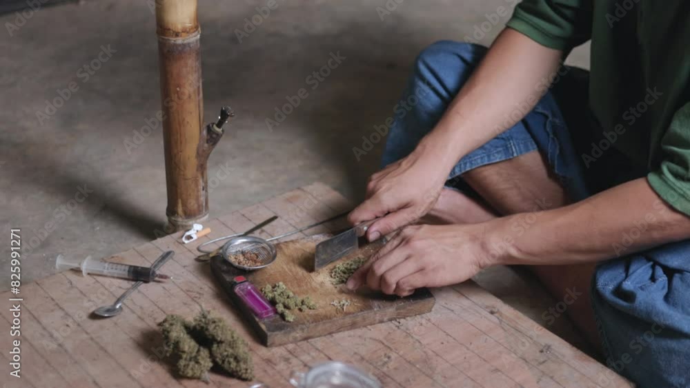 Close-up of a man preparing cannabis medicine for consumption. Man smokes cigarettes and marijuana to relax in a dark room. Marijuana addiction. International anti-drug day concept. Close-up of a man preparing cannabis medicine for consumption. Man smokes cigarettes and marijuana to relax in a dark room. Marijuana addiction. International anti-drug day concept.