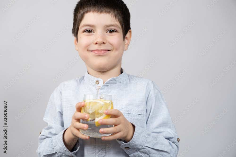 Happy six-year-old boy holding a glass of lemon water in his hands. Happy six-year-old boy holding a glass of lemon water in his hands.