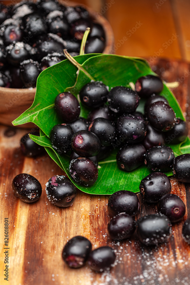 Close-up of 'Indian blackberry' or Jamun (Syzygium cumini) fresh fruits, on a wooden background. Front view. Close-up of 'Indian blackberry' or Jamun (Syzygium cumini) fresh fruits, on a wooden background. Front view.