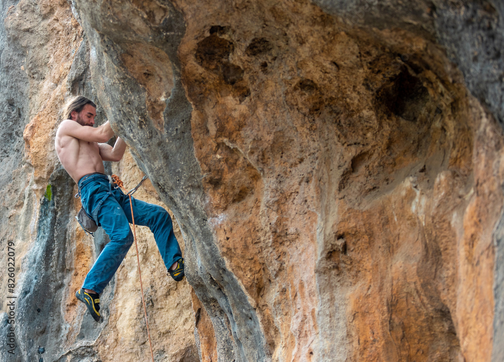 strong rock climber is climbing an overhanging rock.