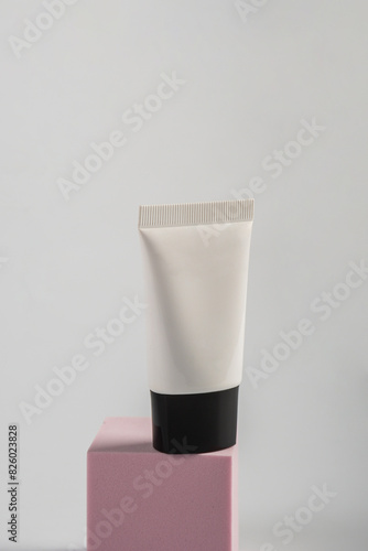 Plastic white tube for cream or lotion. Skin care or sunscreen cosmetic with stylish props on white background.