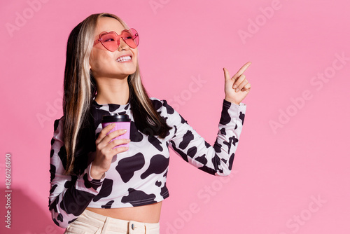 Photo of shiny attractive lady dressed cowskin clothes drink beverage pointing empty space isolated pink color background