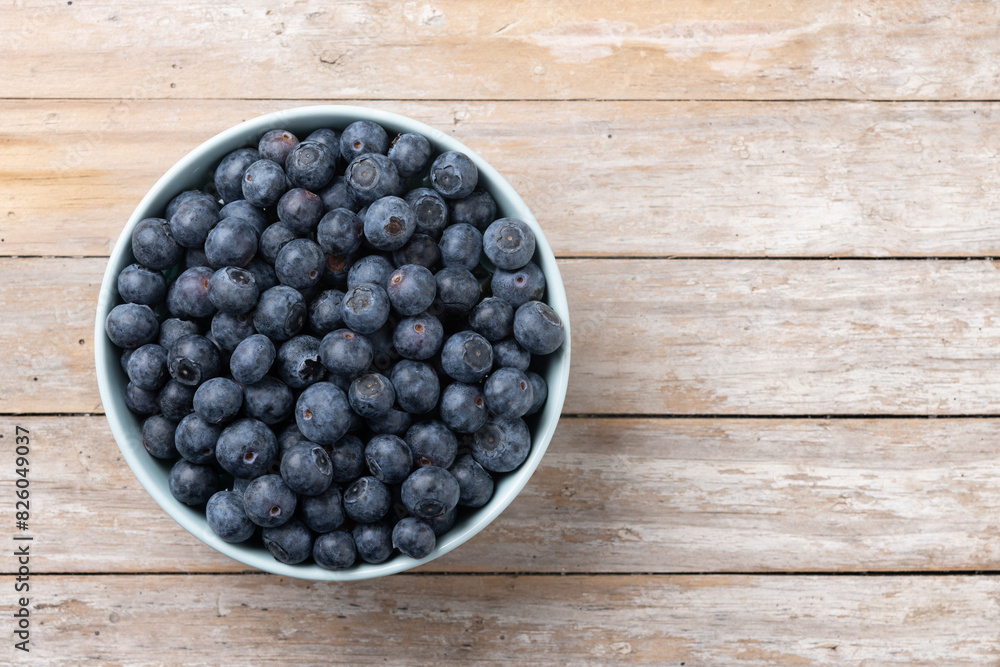 Blueberries in green bowl on wooden table. Top view. Copy space Blueberries in green bowl on wooden table. Top view. Copy space