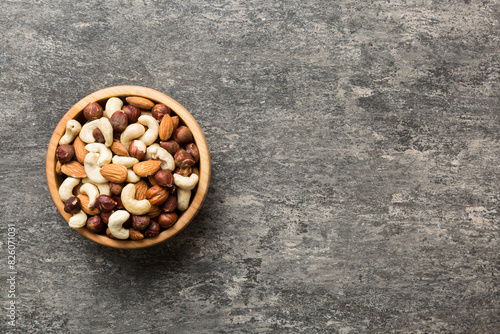 Assortment of nuts in wooden bowl on colored table. Cashew, hazelnuts, walnuts, almonds. Mix of nuts Top view with copy space