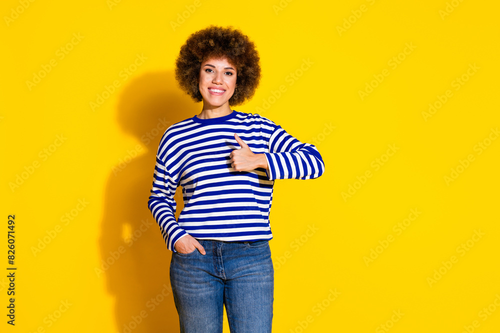 Photo of nice young girl show thumb up empty space wear striped shirt isolated on yellow color background Photo of nice young girl show thumb up empty space wear striped shirt isolated on yellow color background