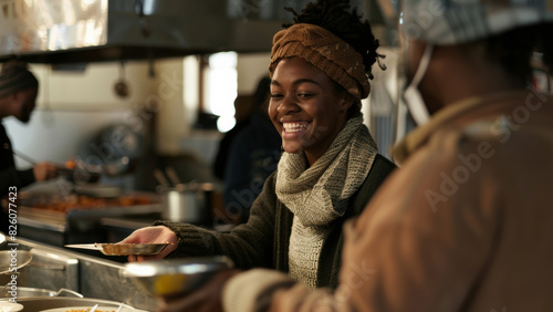 Joyful woman serving food with a bright smile in a bustling community kitchen. photo