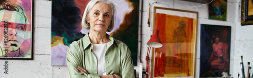 Photography A woman standing in front of colorful paintings on a wall.