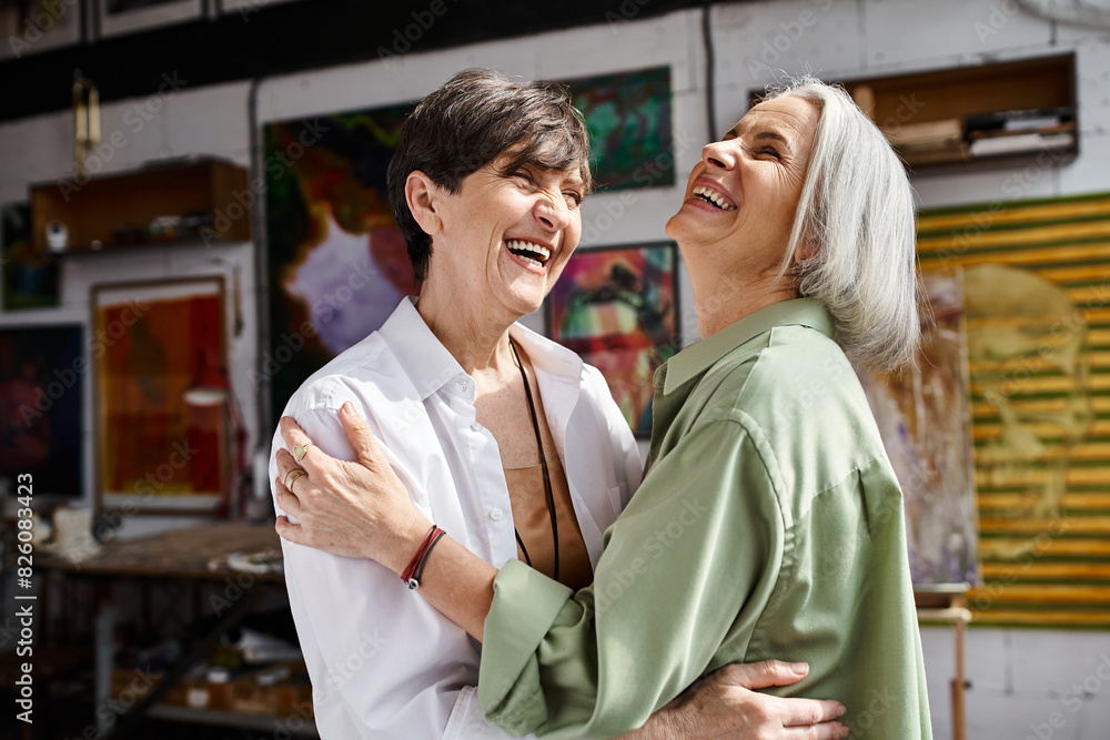 A mature lesbian couple hugging tenderly in an art studio. A mature lesbian couple hugging tenderly in an art studio.
