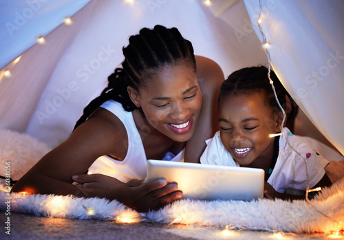 Tablet, relax and mother with kid in tent watching movie, video or show online in bedroom at home. Smile, love and African mom with girl child in blanket fort streaming film on digital technology.