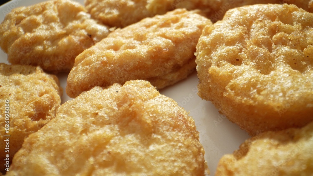 A chicken nugget is a small piece of chicken, either ground or whole, coated in batter or breadcrumbs, then deep-fried or baked until crispy. Shot with 24mm probe macro lens. Fast-food background.
A chicken nugget is a small piece of chicken, either ground or whole, coated in batter or breadcrumbs, then deep-fried or baked until crispy. Shot with 24mm probe macro lens. Fast-food background.