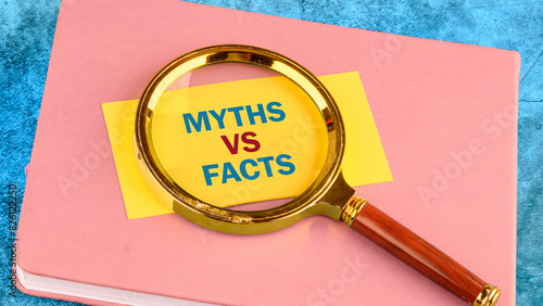 Business, financial and fact vs myth concept. Copy space. Concept words, symbol Fact vs myth on a yellow business card with a magnifying glass on top