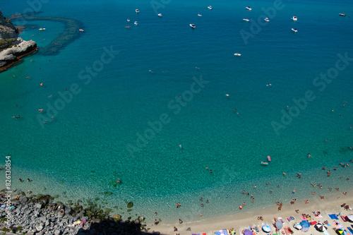 Aerial view of sandy beach with swimming people in sea with transparent blue water in summer. © Alekss