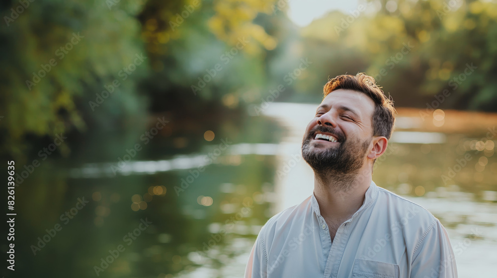 A man in a light shirt stands in front of a serene river landscape, exuding a sense of calm and reflection A man in a light shirt stands in front of a serene river landscape, exuding a sense of calm and reflection