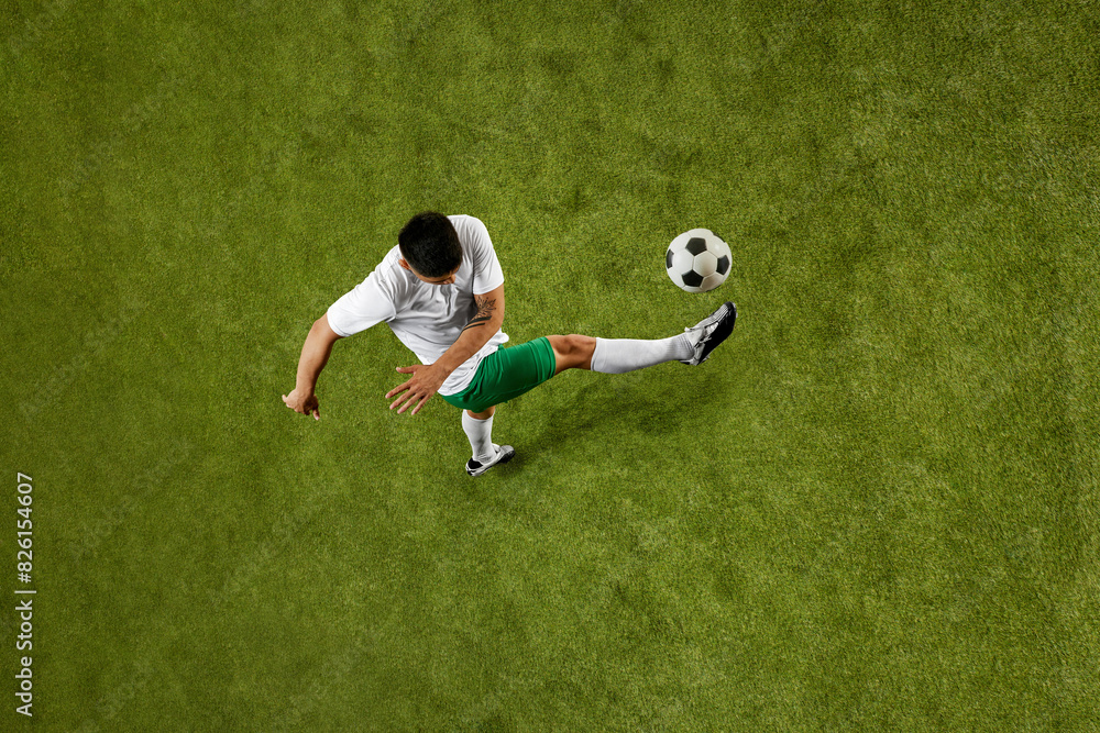 Aerial view. Dynamic shot of young athletic man, wearing comfortable jersey and shorts posing to make perfect pass. Concept of professionals sport, competition, tournament, energy, action. Ad Aerial view. Dynamic shot of young athletic man, wearing comfortable jersey and shorts posing to make perfect pass. Concept of professionals sport, competition, tournament, energy, action. Ad