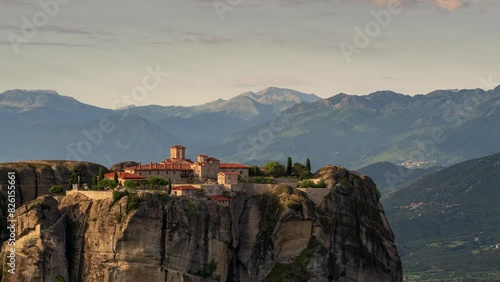 Time lapse with a spectacular view of the Holy Trinity Monastery in Meteora, lit by sun rays against a background of beautiful moving clouds - Thessaly, Greece photo