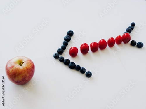 Arrow of fruits indicating to a red apple