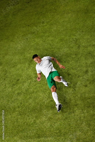 Dynamic photo of young sporty man, soccer player in mid-action, demonstrating hisskills on lush green sports field. Concept of professionals sport, competition, tournament, energy, action. Ad