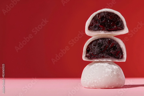 Three sweet red bean mochi stacked against red background in daylight photo