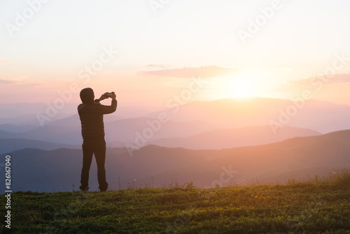 Man Taking Photo of Sunset on Mountain Peak