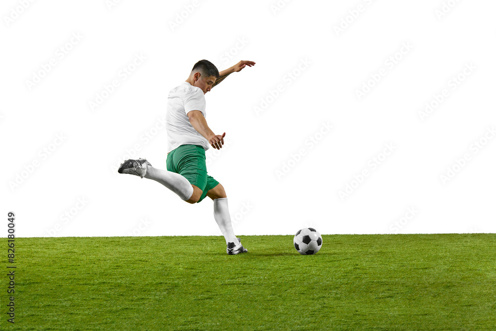 Side view of young fit man, soccer player ready to kick a soccer ball on green grass field against white background. Concept of professionals sport, competition, tournament, energy, action. Ad