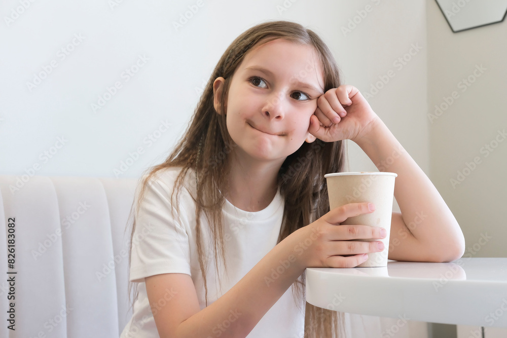 Happy carefree child on vacation enjoying cup of hot chocolate, cocoa, milkshake in cafe. Selective focus. Happy carefree child on vacation enjoying cup of hot chocolate, cocoa, milkshake in cafe. Selective focus.
