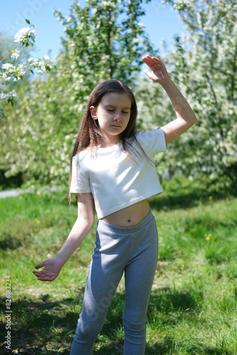 Inspired beautiful girl dancing in a sunny park in summer. Outdoor entertainment. Selective focus. Vertical image.