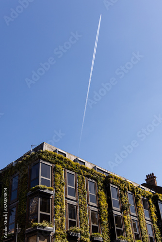 Aircraft chemtrail over a building using green plant walls to aid in carbon emission limitations