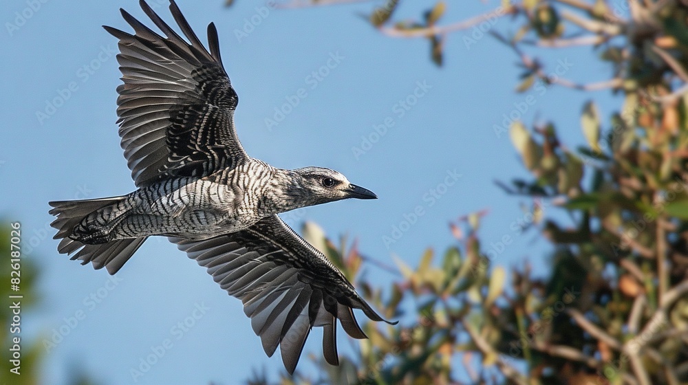 Fototapeta premium A bird glides gracefully against the azure sky, adorned with lush foliage on its back and wings spread wide