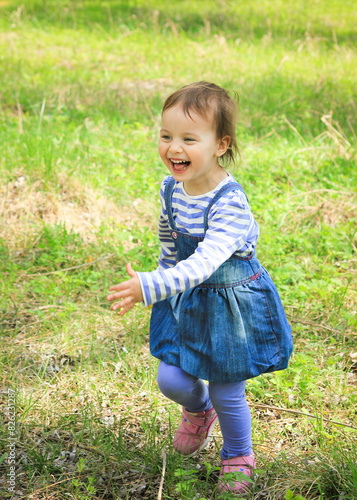 Little adorable smiling girl running in spring outdoors